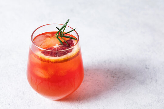 Delicious Blood Orange Cocktail on white table background. Summer cocktails, lemonade, refreshing drinks, low alcohol mocktail concept.
