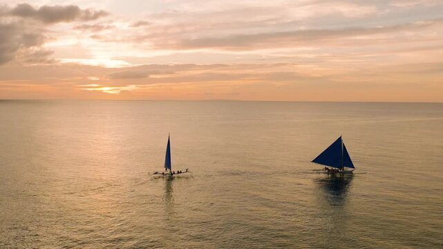 Sunset over the sea and two paraw sailboats in Boracay, Philippines.