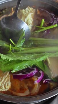 Cooking soup. Seafood and vegetables hot pot served in Asian restaurant. Vietnamese Hot pot cuisine. Steming hot pot over flame at Asian restaurant table.