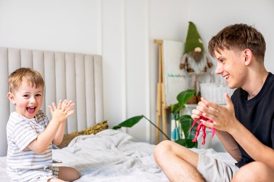 Happy brothers playing with toy figure on bed at home
