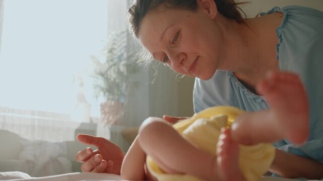 Young mother affectionately talking to and gently stroking her newborn child, expressing immense and care in a bright, sun drenched bedroom, highlighting the beauty of maternity