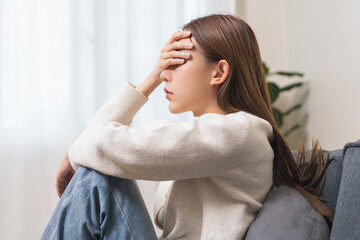 Fototapeta premium Sad, unhappy. Alone asian young woman, girl hand cover face thinking about problem, difficulty, feeling failure and exhausted, suffering from loneliness, grief sorrow and bad relationship or break up.