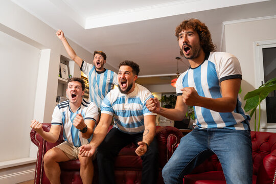 Grupo de amigos argentinos celebrando un gol mientras ven un partido de f&uacute;tbol
