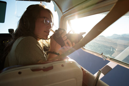 Person using camera inside small plane while flying over landscape