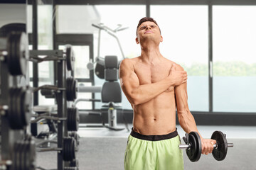 Obraz premium Young man with shoulder pain exercising with weights