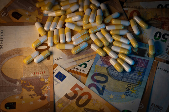Photographie de nombreuses g&eacute;lules dispos&eacute;es sur des billets en euros. Cette image symbolise les d&eacute;penses de sant&eacute;, l&rsquo;industrie pharmaceutique, le remboursement des soins