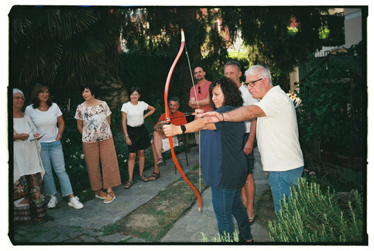Group of People Practicing Archery in a Garden Setting