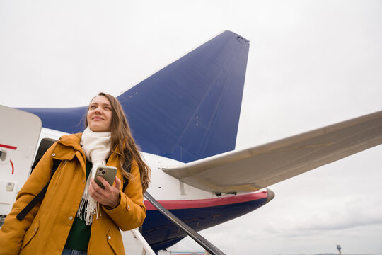Woman Standing Near Airplane While Holding Phone