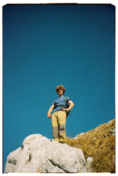 Hiker Stands Proudly on a Rock in a Clear Blue Sky