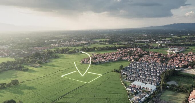 Aerial drone footage of green land featuring digital location marker and highlighted land parcel. Real estate concept representing land for sale, property investment, development opportunity.