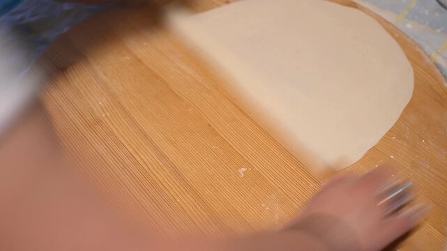 Preparation of Traditional Handmade Phyllo Dough for Greek Pita Using a Long Rolling Pin on a Wooden Board