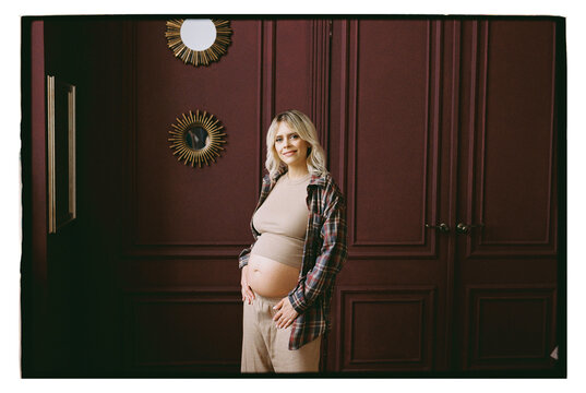 Expecting mother poses in a room with dark walls