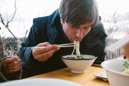 Man eating udon soup outdoors