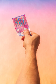 Hand holding Hong Kong banknote against pastel background