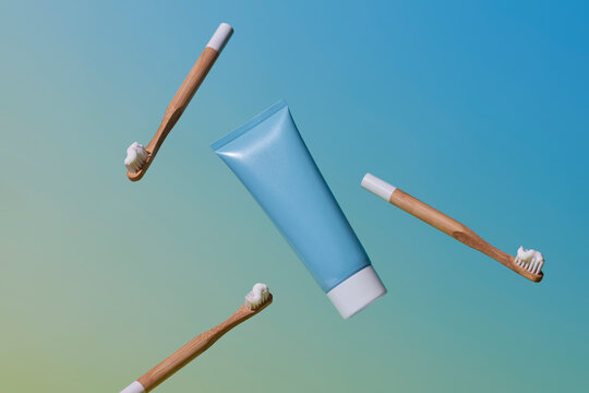 Bamboo toothbrushes and a toothpaste tube floating against a blue