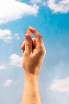 Hand holding euro cent coin against blue sky