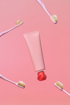 Pink toothbrushes and toothpaste tube floating against a pastel pink