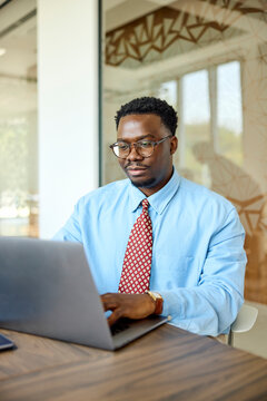 Businessman works indoors, uses a laptop