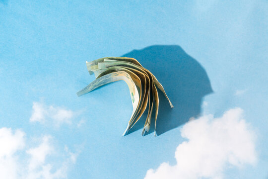 Fanned euro banknotes casting shadow on sky background