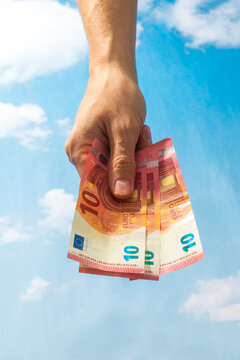 Hand holding euro banknotes against blue sky background