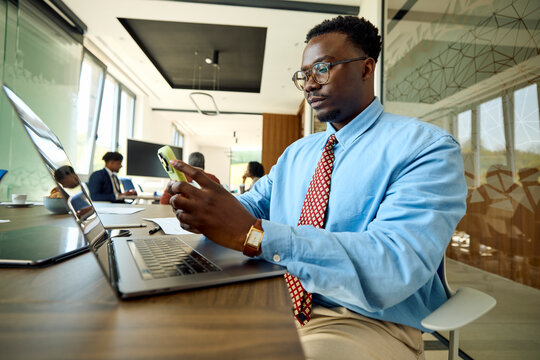 Man sits at the office, using his laptop and a phone