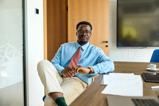 Attractive executive sitting at his desk, looking at the camera