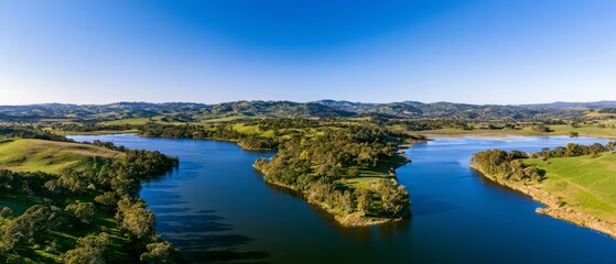 Obraz premium Scenic view of a river winding through green hills during daytime in a rural area