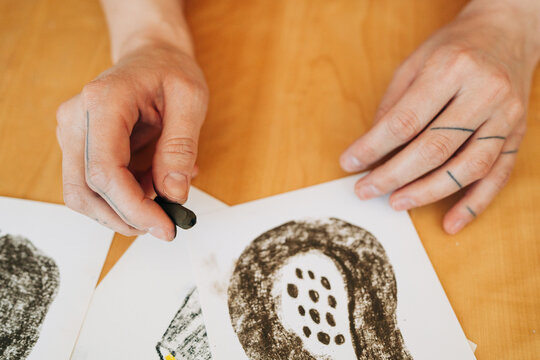 Hands holding charcoal while drawing fruit illustration