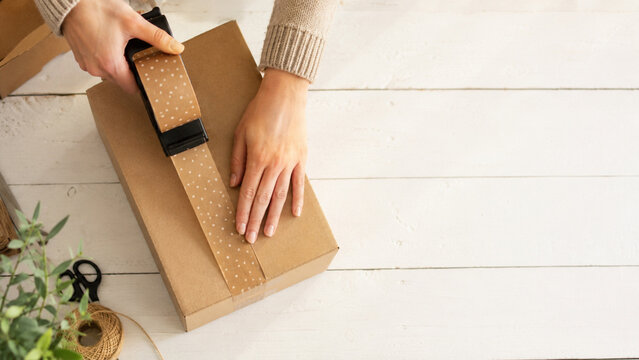 Unrecognizable hands sealing a shipping box with star pattern tape