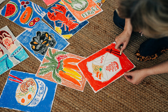Artist drawing colorful illustrations on floor with oil pastels