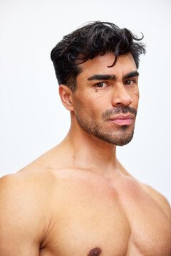 Man with dark hair poses in a studio setting during bright light