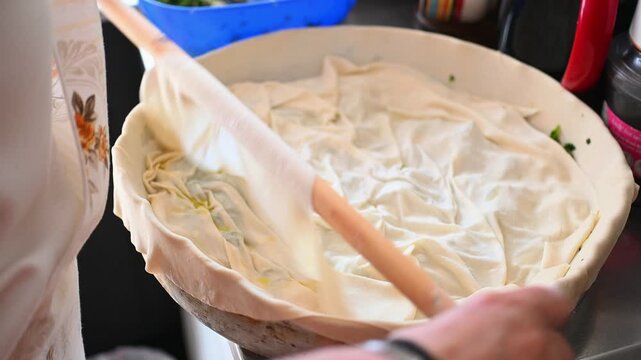 Adding a New Layer of Delicate Phyllo Dough to a Traditional Greek Spinach Pie, Homemade Spanakopita Preparation with Olive Oil