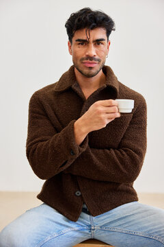 Young man enjoys coffee while seated indoors