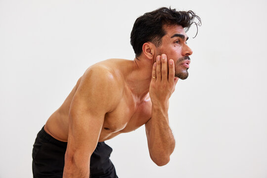 Man touches face during fitness routine in a gym setting