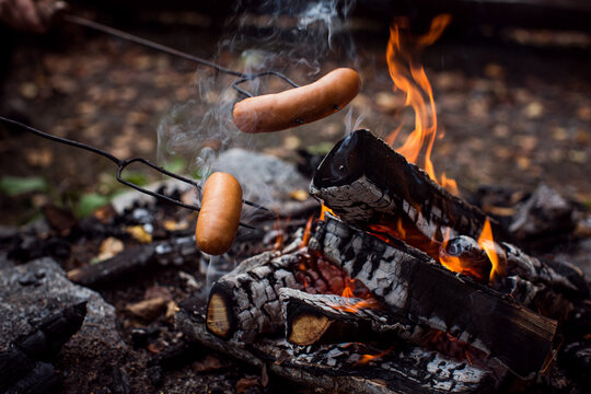 sausages cooking on top of bonfire