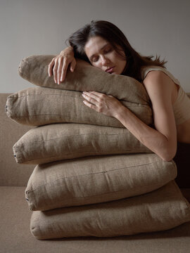 Woman Resting on Stacked Pillows in a Simple Room Setting
