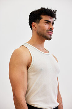 Man in a tank top stands in a studio with a calm expression