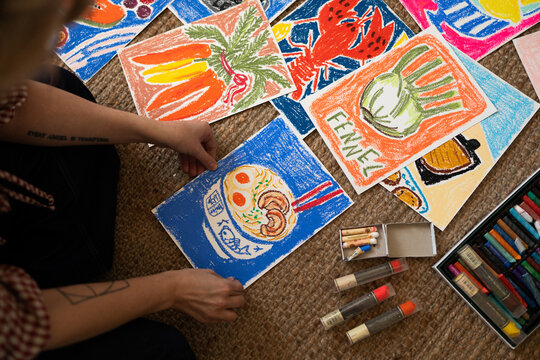 Close-up of colorful pastel drawings and art supplies on floor