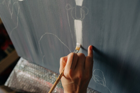 Close-up of artist painting vertical white stroke on canvas