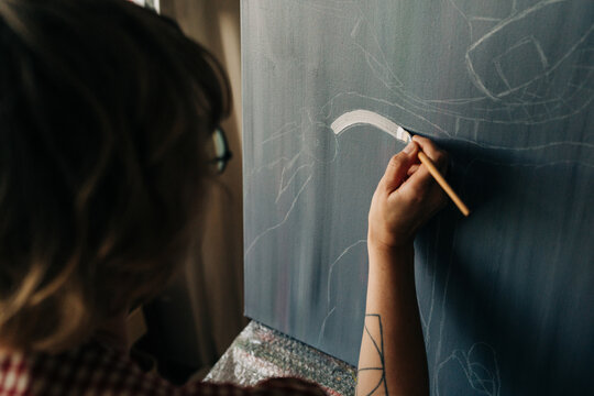 Close-up of artist painting white brushstroke on canvas