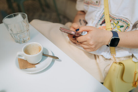 Anonymous woman typing on her smartphone in cafe