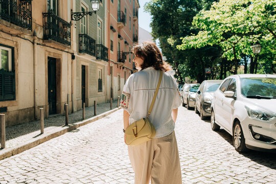Woman Walking on Quiet Cobblestone Street in Summer Sunlight