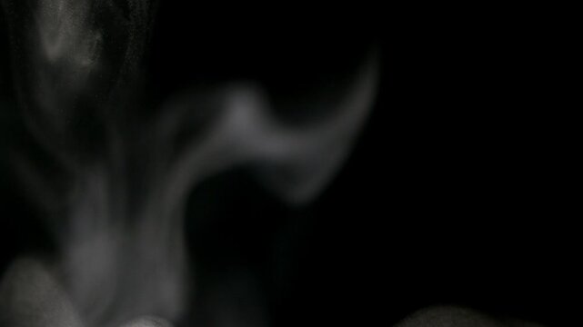 Soft white smoke swirling and rising slowly against a deep black background for a cinematic visual effect.