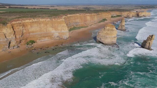 Aerial forward drone shot approaching the iconic Twelve Apostles limestone stacks with ocean waves crashing below, Great Ocean Road, Victoria, Australia.