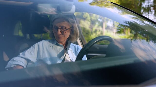 Happy Caucasian old retired elderly woman sitting inside new own car luxury auto fastening seat belt smiling cheerful enjoying driving automobile test drive carefree mature aged female driver smile