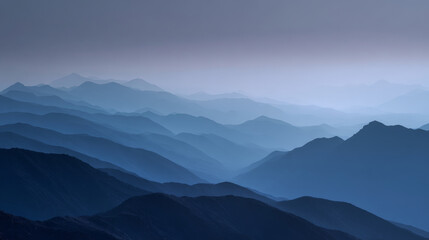 Fototapeta premium Serene blue mountain landscape with layers of misty hills fading into the distance under a tranquil sky. Peaceful natural scenery evokes calmness and awe in a minimalist composition