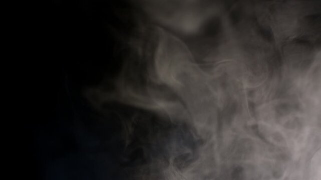 Abstract white smoke plumes rising slowly against a deep black background for creative visual design projects