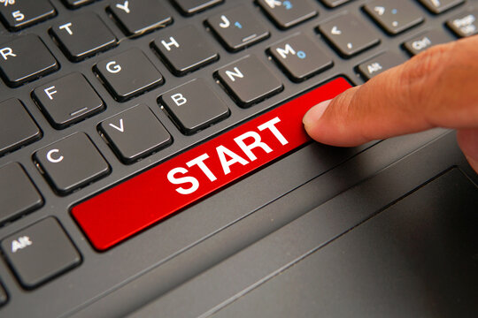 Close up of a computer keyboard with a finger pressing a red start key, representing taking action, new beginnings, business initiatives, motivation, goal achievement, and personal growth concepts.
