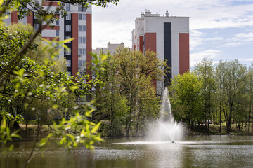 Fototapeta premium Residential buildings by lake with fountain in daytime