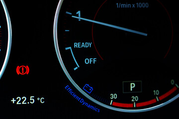 Fototapeta premium Car dashboard with illuminated warning indicators and tachometer.